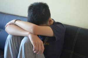 Sad teen with head in his arms