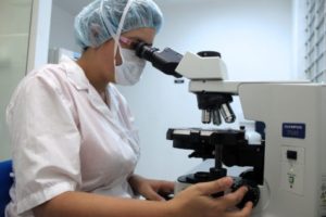 Lab worker looking through microscope