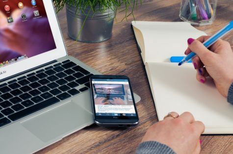 Smartphone on laptop while person works