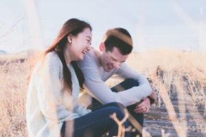 Couple sitting in field laughing