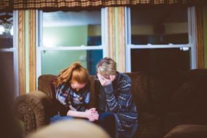 Women crying together on couch