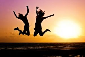 Girls jumping up in the air in front of sunset