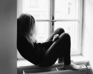 Sad teen alone at window