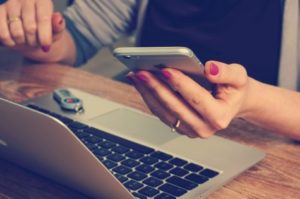 Woman using iPhone and laptop