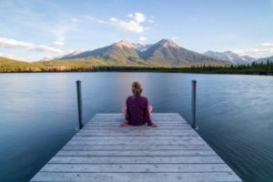 Woman sitting on dock looking out at mountains