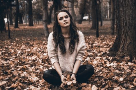 Upset young woman sitting in leaves