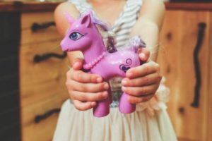 Child holding purple pony toy