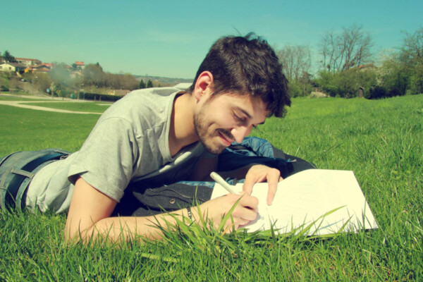 Man lying in grass writing