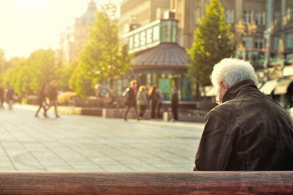 Older, retired person sitting alone on a bench