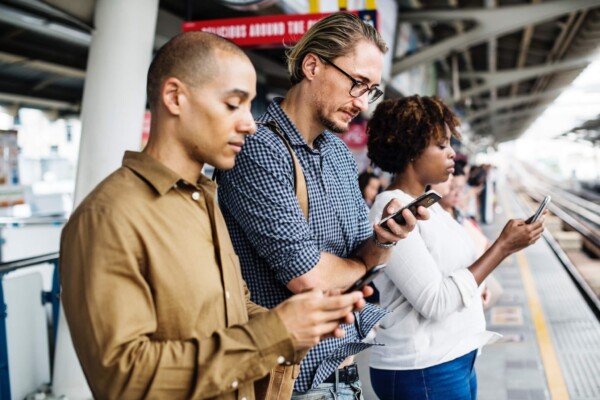 People staring at their smartphones on a subway platform