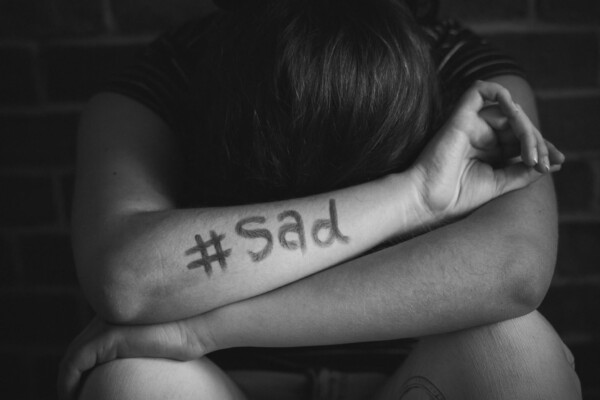 Upset person alone with "#sad" on arm