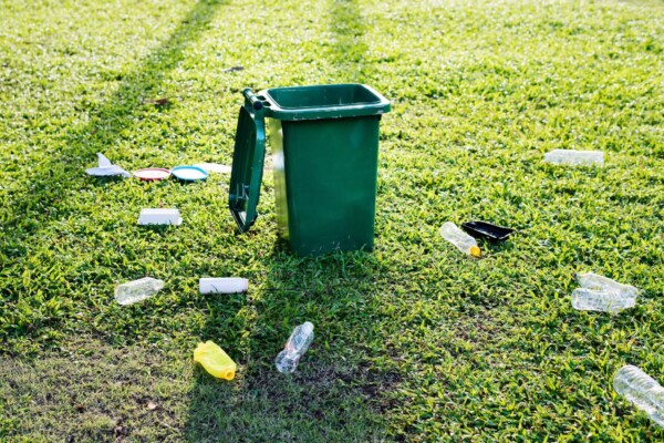 Recycling can with garbage surrounding it