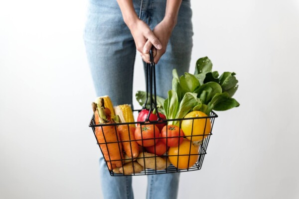 Shopper carrying basket of fresh vegetables