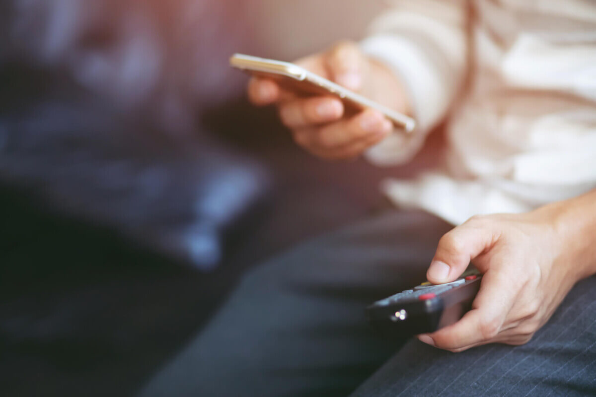 Person using their phone or social media while watching TV