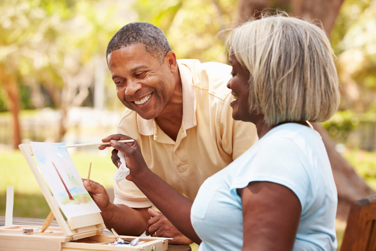Senior Couple Sitting At Outdoor Table Painting Landscape