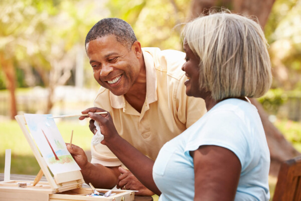 Senior Couple Sitting At Outdoor Table Painting Landscape
