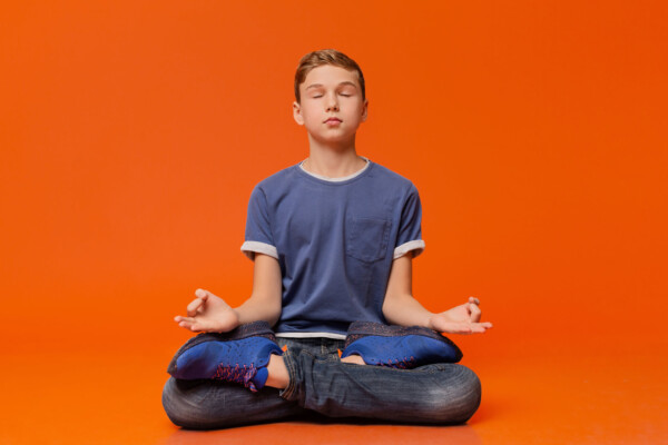 Boy sitting on floor practicing mindfulness meditation