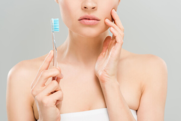Woman with toothache brushing her teeth