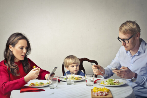 Parents looking at phones while eating dinner