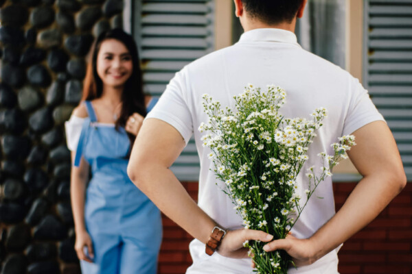 Man surprising woman with flowers