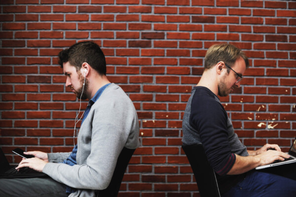 Two men sitting down hunched over their laptops
