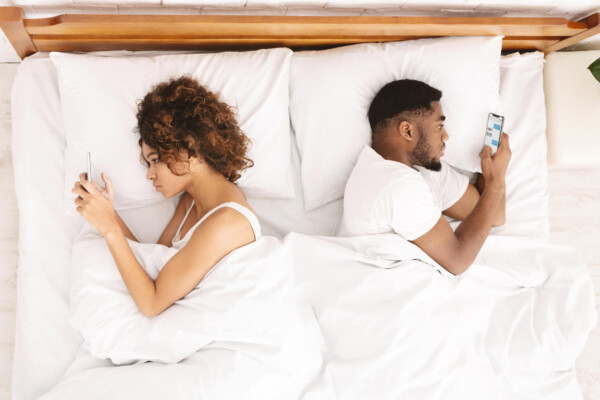 Couple using their smartphones while in bed