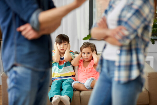 Siblings covering ears while parents fight