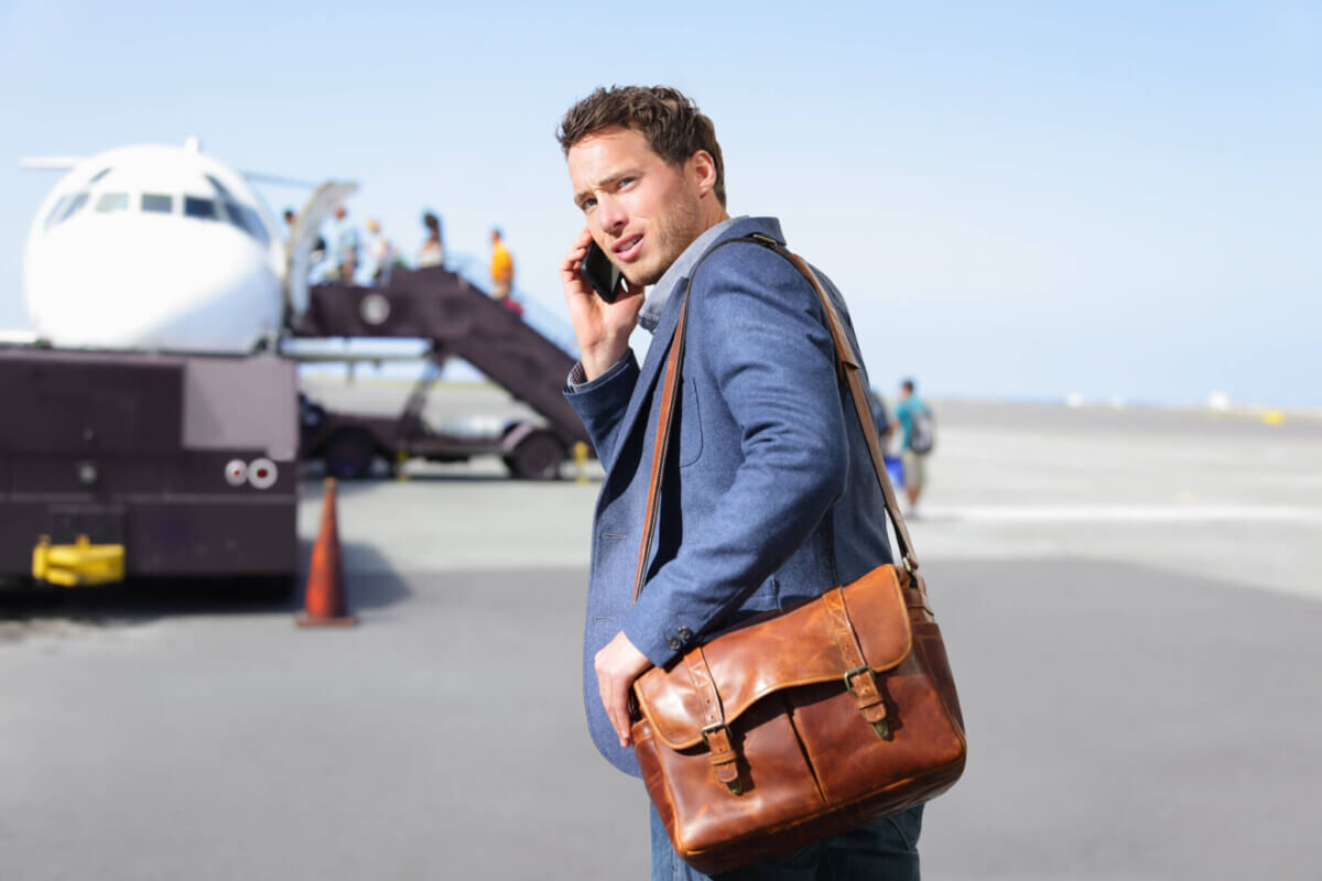Airport businessman on smartphone by plane