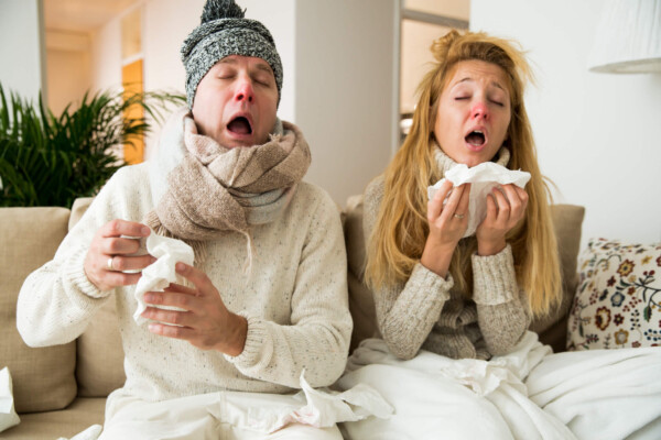 Couple sick at home, sneezing, blowing nose