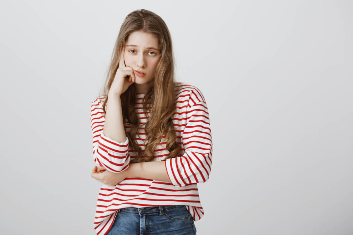 Girl almost sleeps from boredom during class. Portrait of indifferent tired female model supporting head with hand, slouching with drooping eyes, being interested in event, exhausted during date
