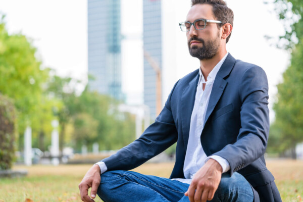 Man practicing meditation in city park