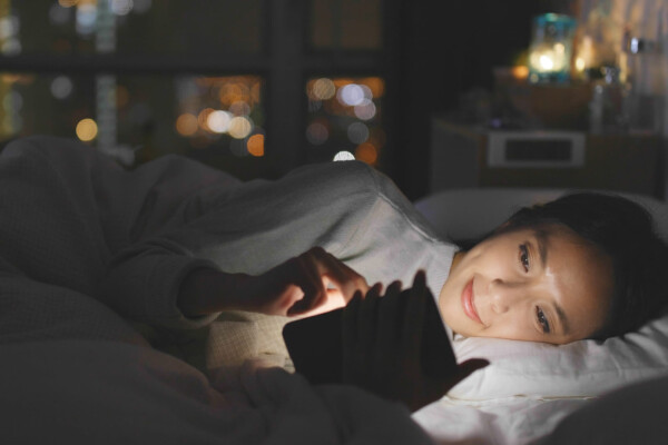 Woman looking at phone in bed, blue light in face
