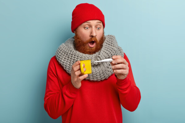 Sick man looking at thermometer