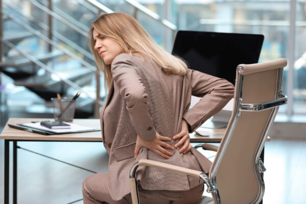 Woman battling lower back pain at office