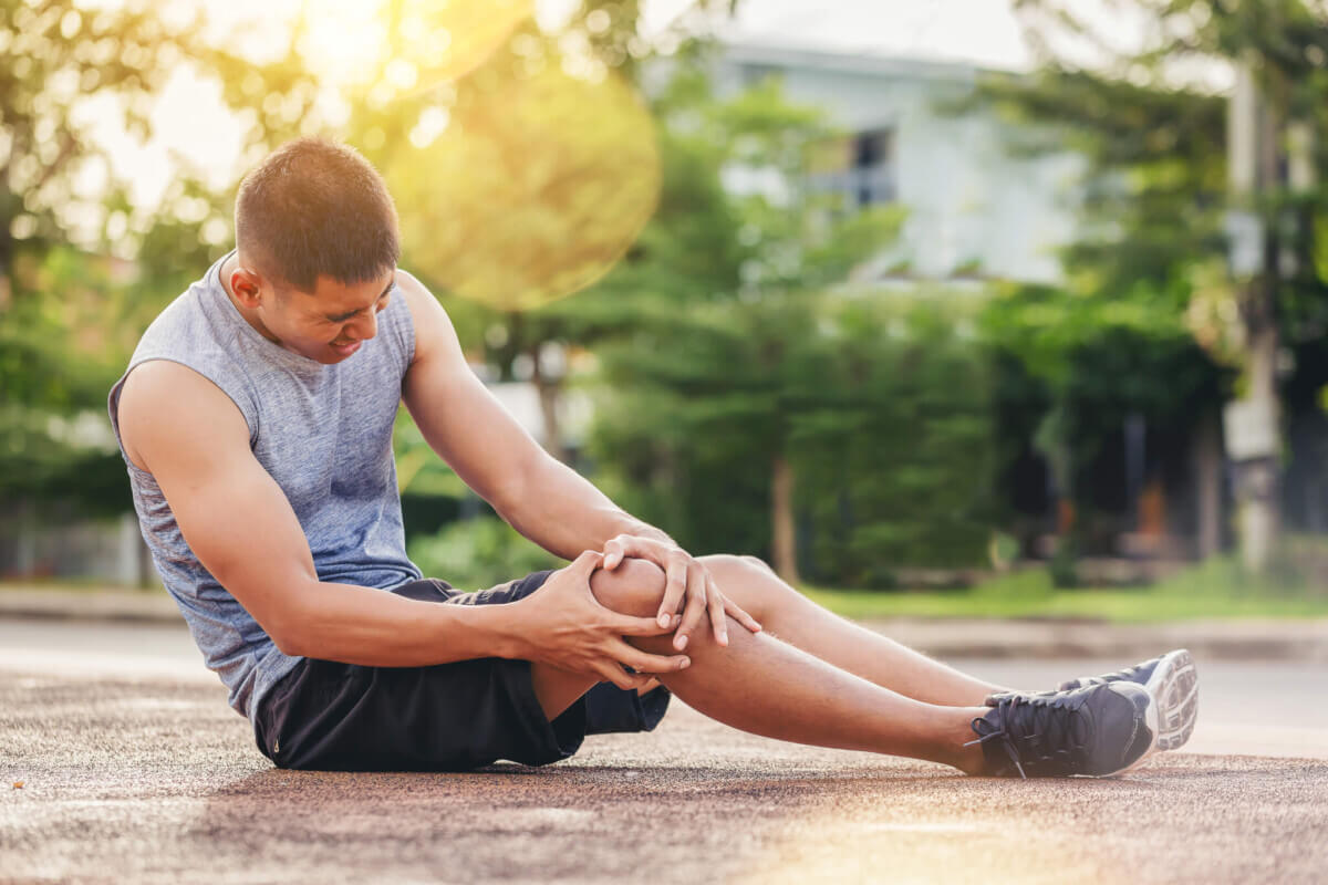 Runner man with sports running knee injury. Hands holding knee with painful.