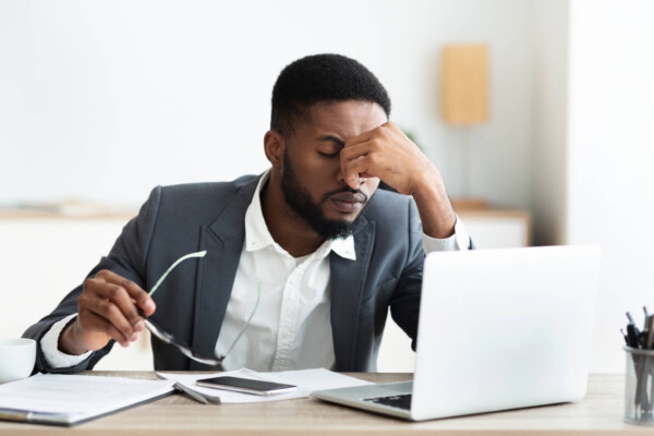 Stressed man at work, suffering from headache at office