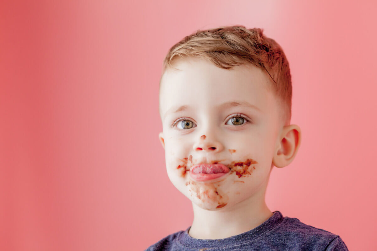 Little boy eating chocolate. Cute happy boy smeared with chocolate around his mouth. Child concept.