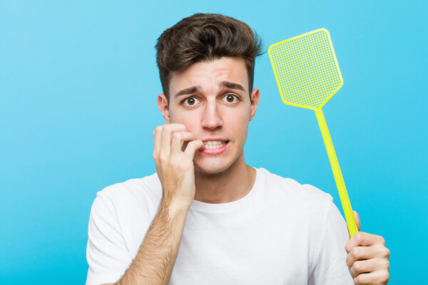 Man with fly swatter appearing nervous