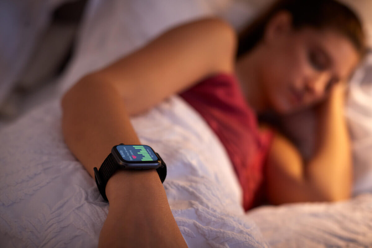 Woman sleeping in bed focusing on the smart watch she is wearing