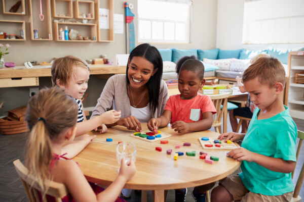 Preschool teacher showing students how to build with wooden blocks