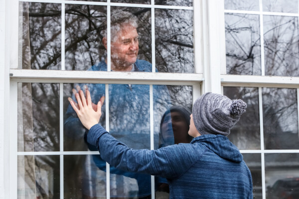 Social distancing - man at window during coronavirus lockdown