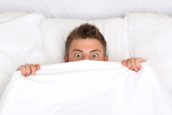 Scared man in bed having bad dream or nightmare