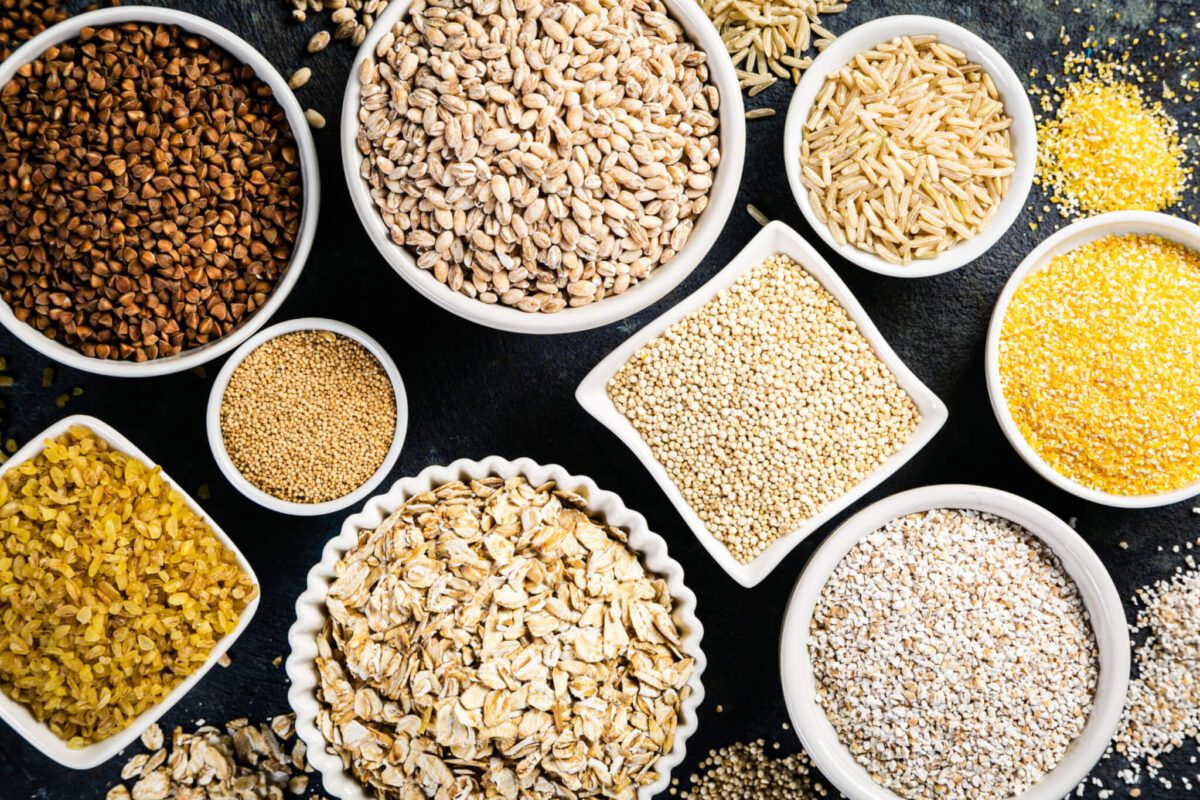 Selection of whole grains in white bowls – rice, oats, buckwheat, bulgur, porridge, barley, quinoa, amaranth