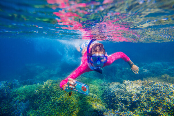 Girl or woman scuba diving with smartphone, taking selfie or streaming video underwater