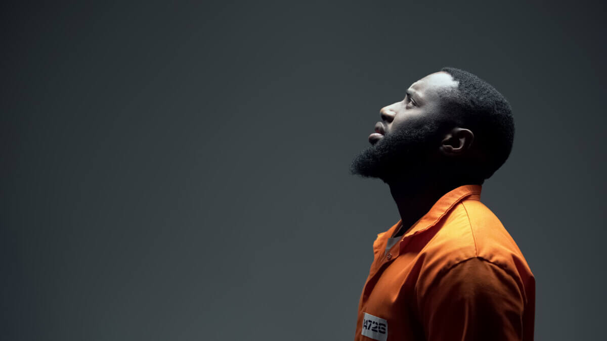 African American imprisoned male praying looking up at light, talking to god, faith
