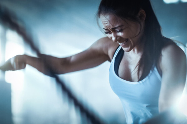 Woman having vigorous workout, strenuous exercise routine with ropes