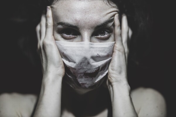 Woman in mask stressed during COVID-19 / coronavirus pandemic