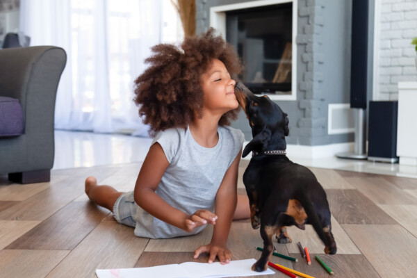 Dog kissing cute little girl