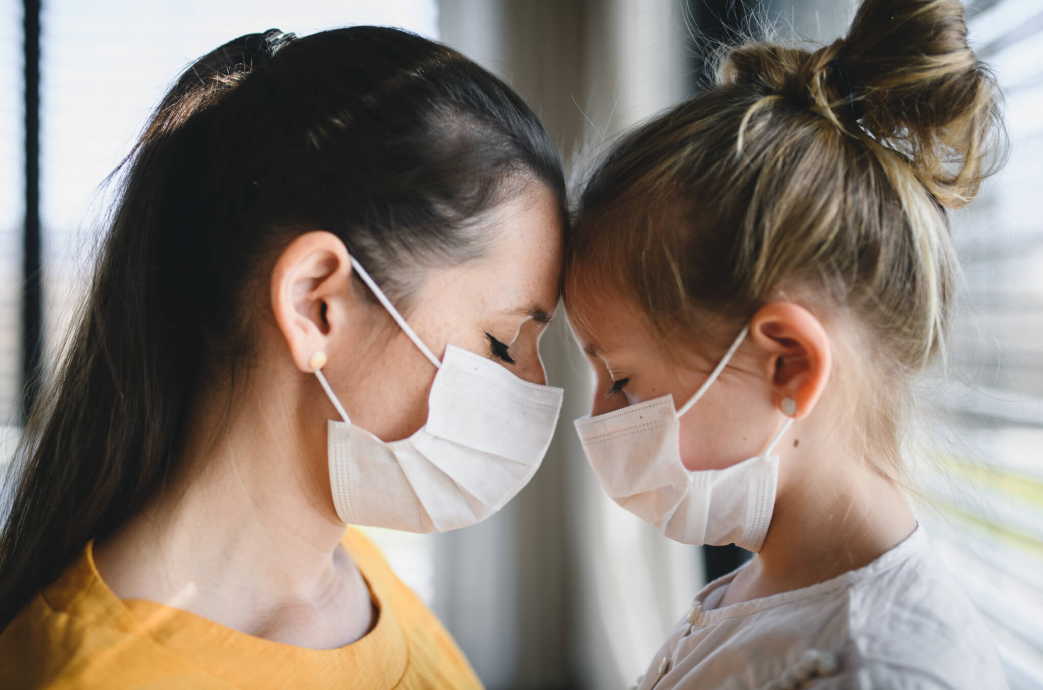 Mother, daughter wearing masks during coronavirus / COVID-19 outbreak, sad or grieving