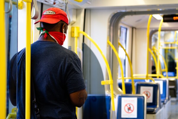 Man wearing a bandana or neck gaiter on train as face covering
